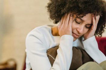 Mulher com as mãos no rosto triste em luto.