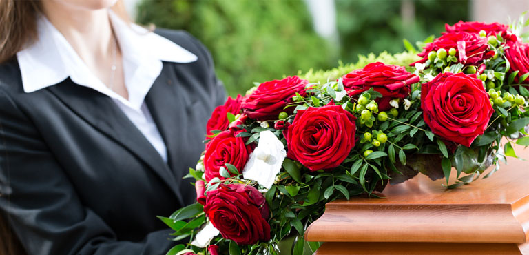 mulher de preto segurando coroa de flores em velório