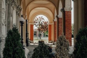 Um edifício durante o dia com um arco que leva ao jardim