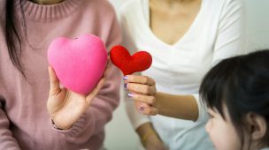 Duas mulheres e uma criança segurando um coração.