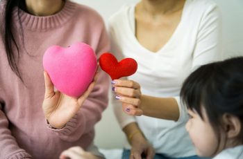 Duas mulheres e uma criança segurando um coração.
