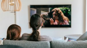 Imagem de duas mulheres no sofá assistindo filme na sala de televisão