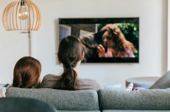 Imagem de duas mulheres no sofá assistindo filme na sala de televisão