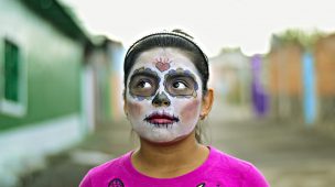 Criança menina com pintura no rosto comemorando o Dia dos Mortos no México.