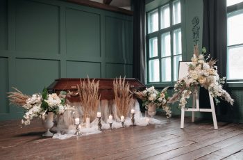 caixão com várias coroas de flores em um salão, preparado para o velório, uma das várias cerimônias de despedida que existem