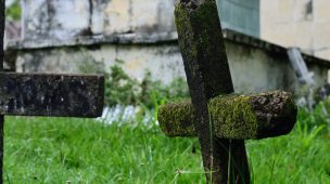 Imagem de um cemitério com uma cruz na grama