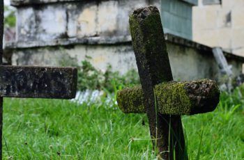 Imagem de um cemitério com uma cruz na grama