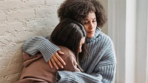 Imagem de duas mulheres abraçadas com aparência triste