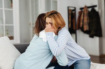 Imagem de uma mulher chorando sendo consolada por outra pessoa